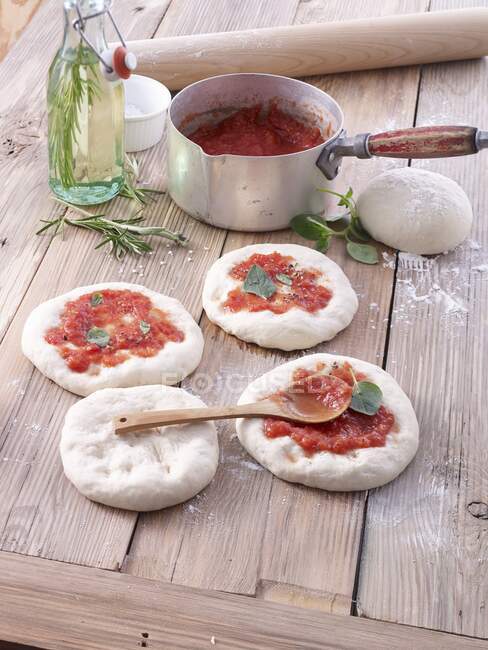 Невыпеченные пиццы с томатным соусом — стоковое фото