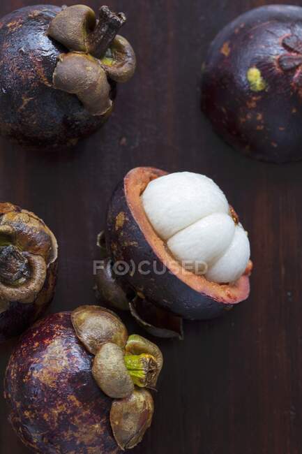 Tropische Früchte ganz und in Scheiben geschnitten auf Holzbrett — Stockfoto