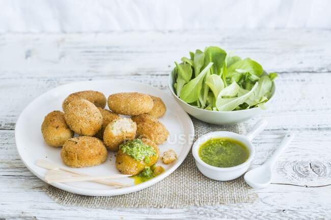 Breaded fishcakes with green sauce and salad — Stock Photo