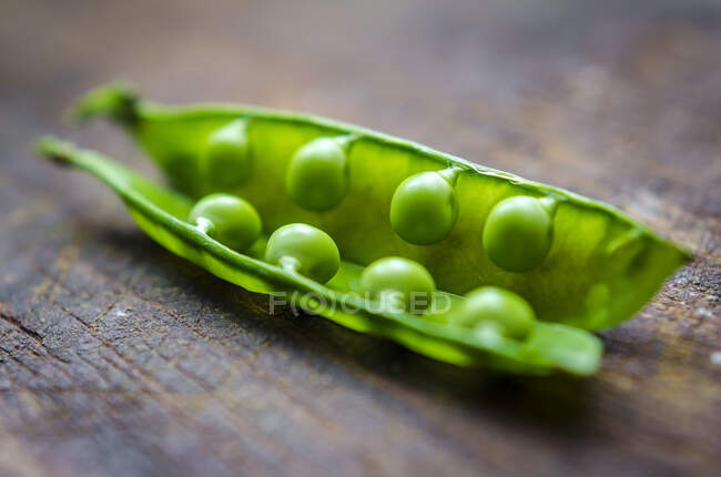 Close up of fresh green peas in a pod on a dark wooden background — Stock Photo