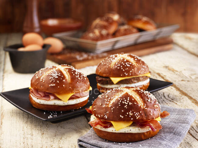 Lye bread rolls with bacon, cheese and fried egg — Stock Photo