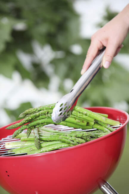 Green asparagus on a round barbecue — Stock Photo