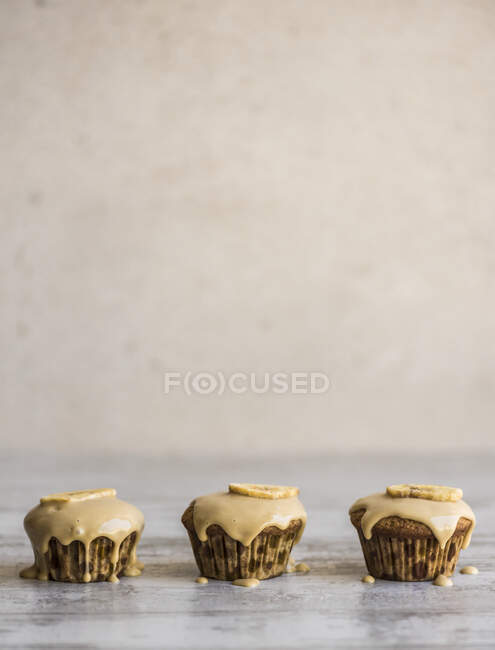 Three  cupcakes with liquid cream and banana slices — Stock Photo