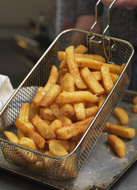 Batatas fritas que drenam em uma cesta — Fotografia de Stock