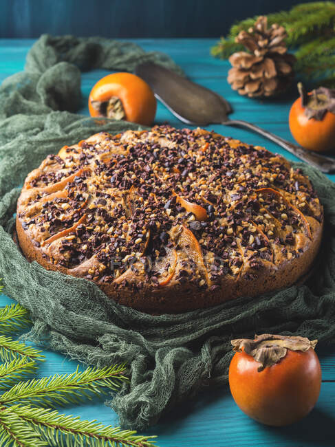 Vollkornkuchen mit Kaki garniert mit rohen Kakaofedern und Walnüssen — Stockfoto