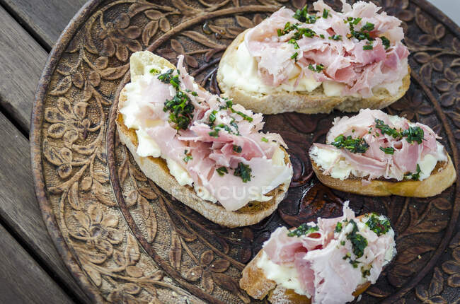 Bruschetta toasted sliced baguette, ciabatta and sourdough bread with spreadable soft cheese and ham drizzled with herbs — Stock Photo