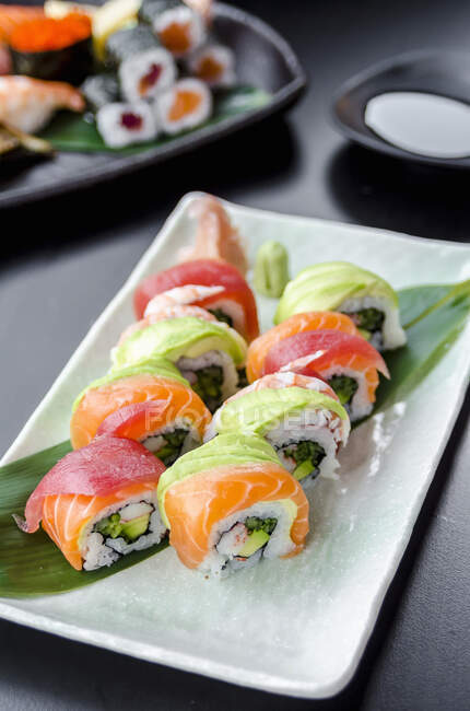Japanese platter of rainbow rolls maki, inside out seaweed and rice roll filled with cucumber, mayonnaise, avocado, crub stick topped with fresh salmon, tuna, avocado and prawn — Stock Photo
