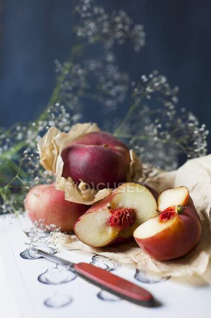 Fresh peaches, whole and halved, on brown paper — Stock Photo