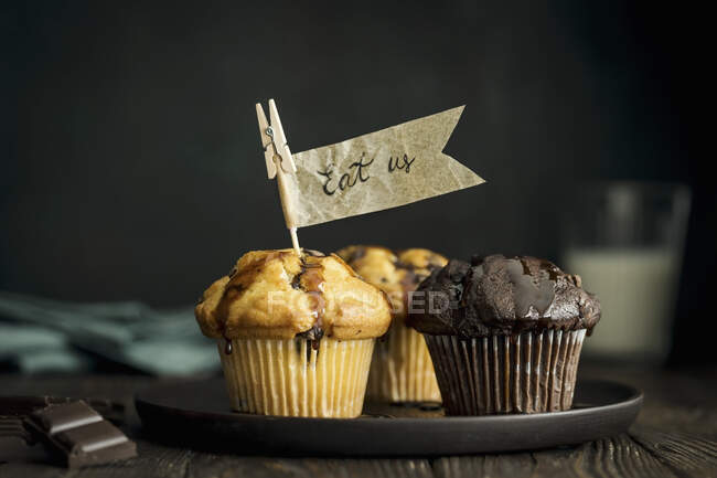 Vanilla and chocolate muffins with chocolate chunks and paper flags — Stock Photo