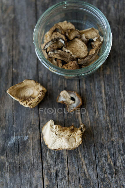 Cogumelos porcini secos em jarra e na superfície de madeira — Fotografia de Stock