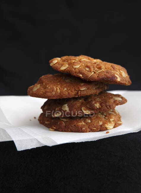 A stack of oatmeal cookies on paper against a black background — Stock Photo
