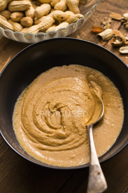 Домашнее арахисовое масло в миске с ложкой — стоковое фото