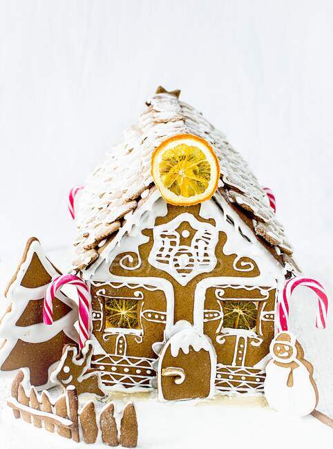 Gingerbread house with candy canes and dried orange slice — Stock Photo