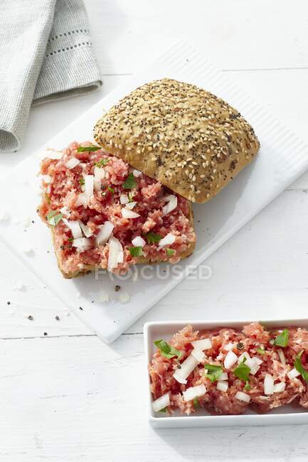 A crusty bread roll topped with ground pork sausage and onion — Stock Photo