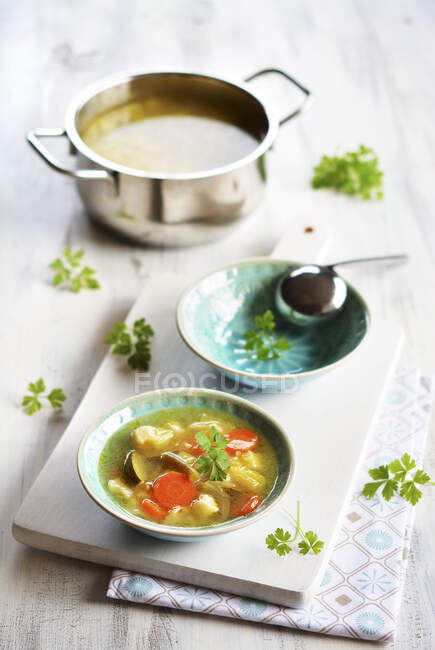 Sopa de verduras en un tazón pequeño en una tabla con una toalla de cocina - foto de stock
