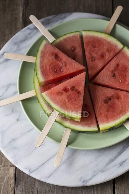 Wedges of watermelon on lollipop sticks in plate — Stock Photo