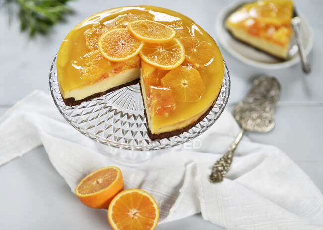 Pastel de queso naranja con una base de chocolate, cubierto con rodajas de naranja y jalea de naranja (vegetariano) - foto de stock