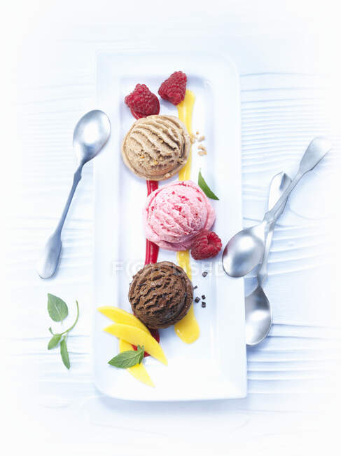 Various ice cream scoops with mango and raspberry sauce — Stock Photo