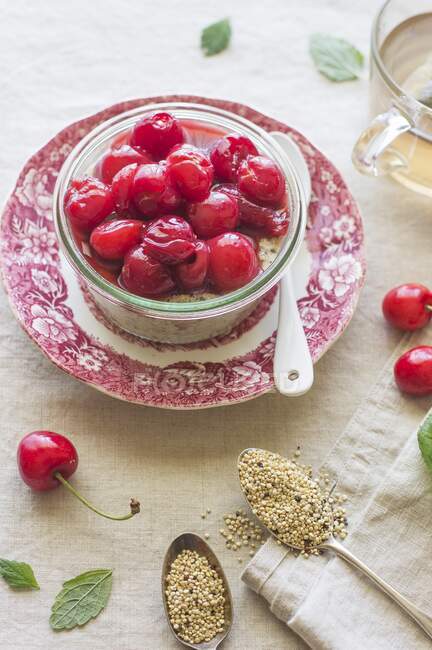 Jar of quinoa porridge with cherries in syrup and fresh berries on table — Stock Photo