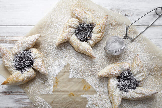 Estrellas pasteles con ciruelas y azúcar en polvo sobre papel de hornear - foto de stock