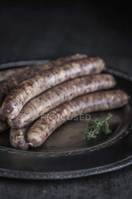 Sausages on serving dish with thyme spring — Stock Photo