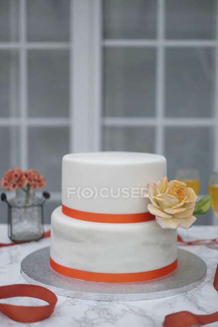 Un pastel de boda de dos niveles decorado con rosas - foto de stock