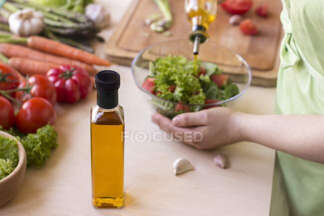 Tiro cortado de pessoa Preparação de salada com óleo de colza, alface, tomates, cenoura, alho, espargos — Fotografia de Stock