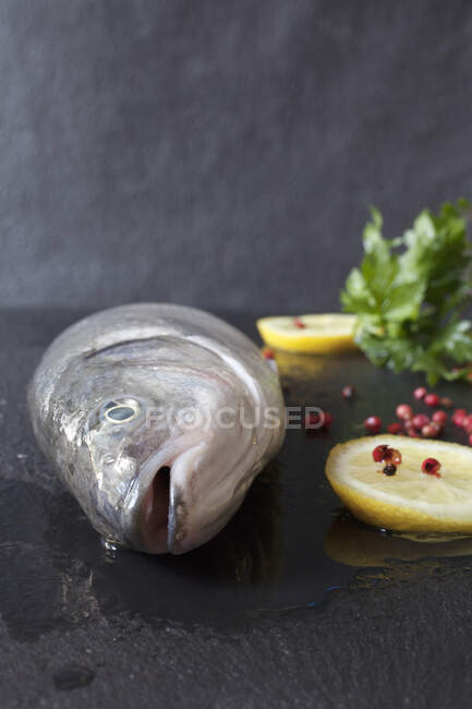 Fresh Whole Branzini with Lemon Slices and Red Pepper Corns — Stock Photo
