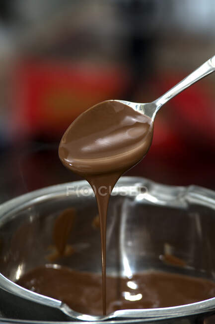Розтоплений шоколад капає з ложки в миску. — стокове фото