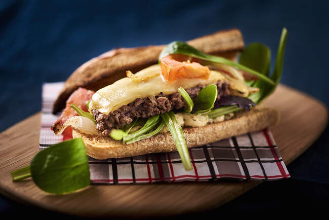 A sandwich with minced meat, cheese and lambs lettuce — Stock Photo