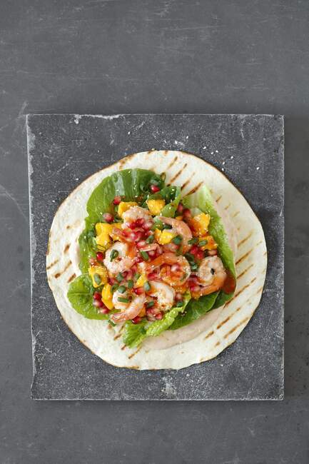 Tortilla wrap with shrimps and mango on stone surface — Stock Photo