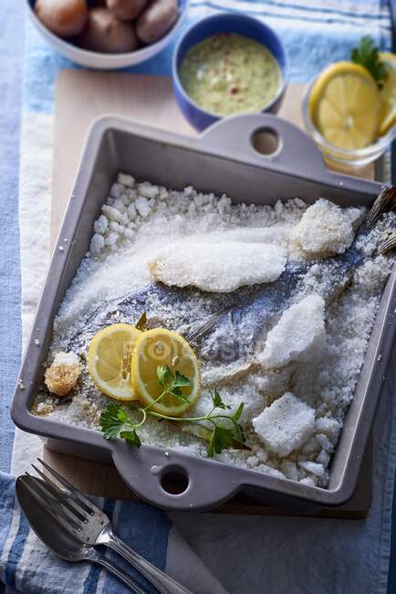 Fish cooked in salt crust with lemons and herbs — Stock Photo