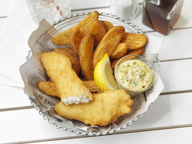 Pesce e patatine fritte con salsa e limone — Foto stock