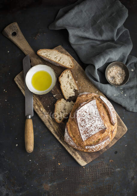Bread on board with olive oil and bowl of himalayan salt on cloth — Stock Photo