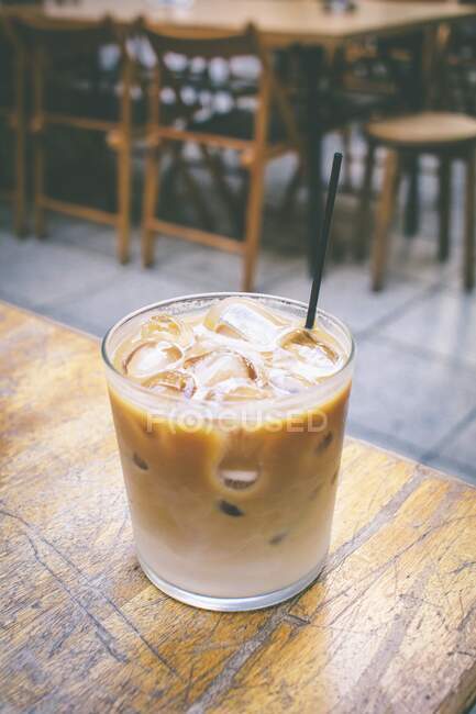 Creamy drink with coffee liqueur, ice and straw in glass — Stock Photo