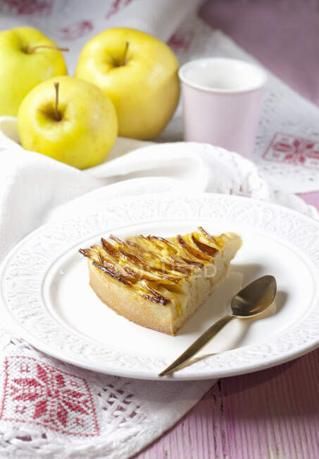 Una rebanada de tarta de manzana y manzanas frescas - foto de stock