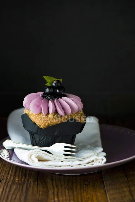 A cupcake decorated with blackcurrants — Stock Photo