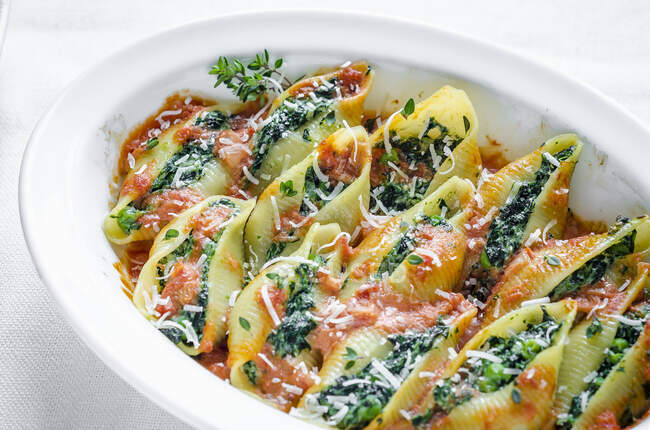 Shell pasta with a spinach and ricotta filling in tomato sauce with Parmesan — Stock Photo
