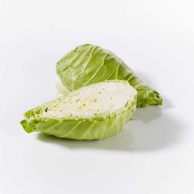 Pointed cabbages, whole and halved, on a white surface — Stock Photo