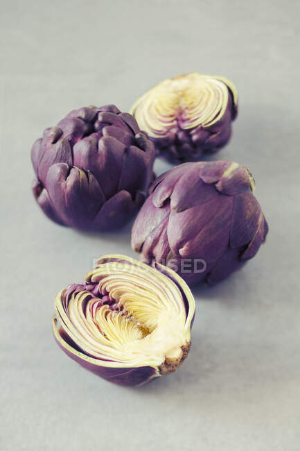 Baby purple artichokes, whole and halved — Stock Photo