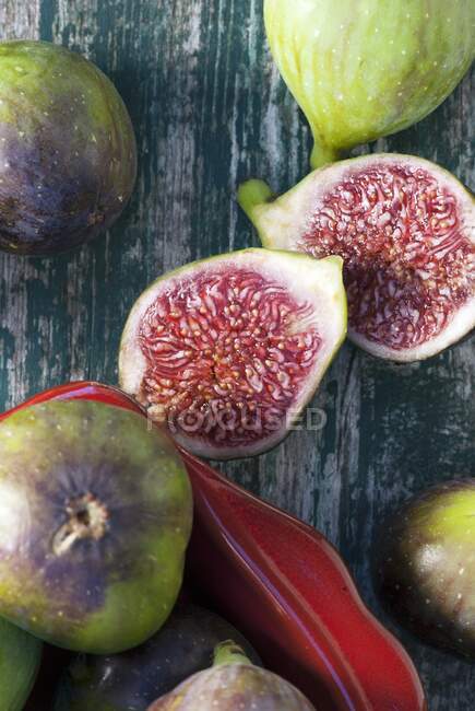 Fresh whole and halved figs on wooden surface and in ceramic tin — Stock Photo