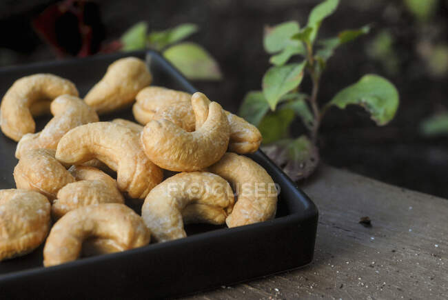 Cashew nuts roasted and salted on a black plate — Stock Photo