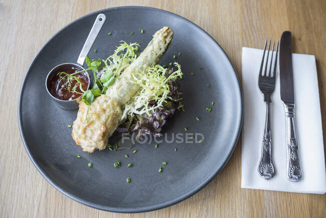 Deep fried zucchini flowerstuffed with mozzarella cheese served on a crispy leaf salad and sweet chilly sauce on a grey plate — Stock Photo