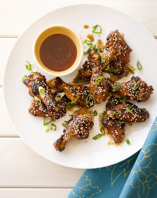 Grilled honey and sesame seed chicken wings on white wooden table — Stock Photo