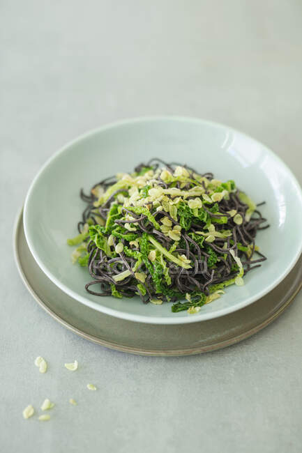 Black bean noodles with savoy cabbage and fried green rice (vegan) — Stock Photo