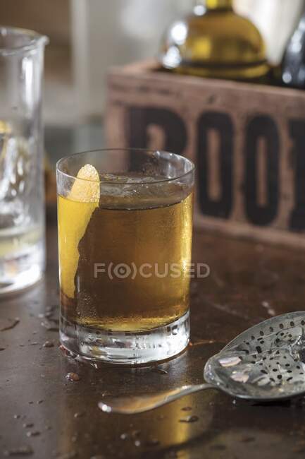 Старомодный коктейль, украшенный ломтиком апельсиновой кожуры в стакане — стоковое фото