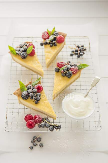 A vanilla tart decorated with fresh berries and cut into slices — Stock Photo