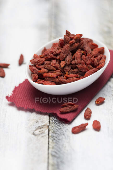 Dried goji berries in bowl on red cloth — Stock Photo