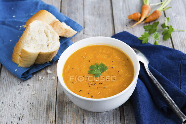 Pepper and carrot soup with cumin, parsley and baguette — Stock Photo
