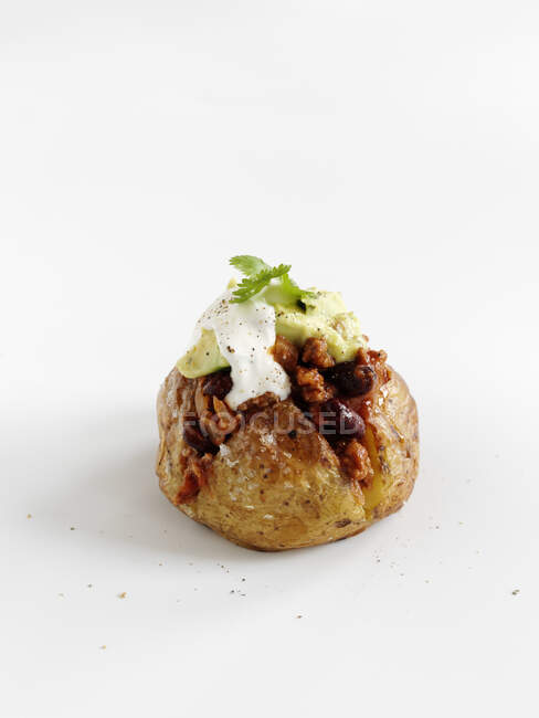 Whole baked potato with chili, avocado and melted cheese — Stock Photo